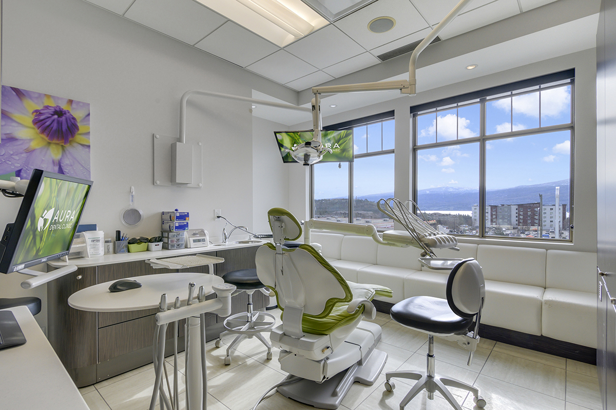 A modern dental clinic with a dental chair, treatment tools, monitors, and large windows showcasing a view.