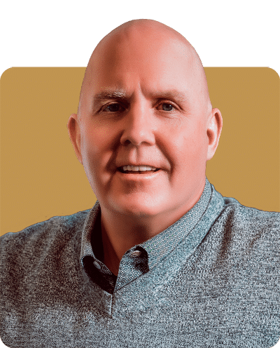 A smiling man wearing a gray sweater is pictured against a gold background.