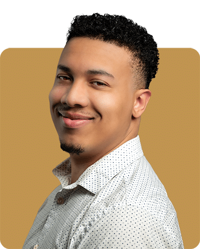 A smiling man with short, curly hair wearing a light-colored, collared shirt is posed against a solid background.