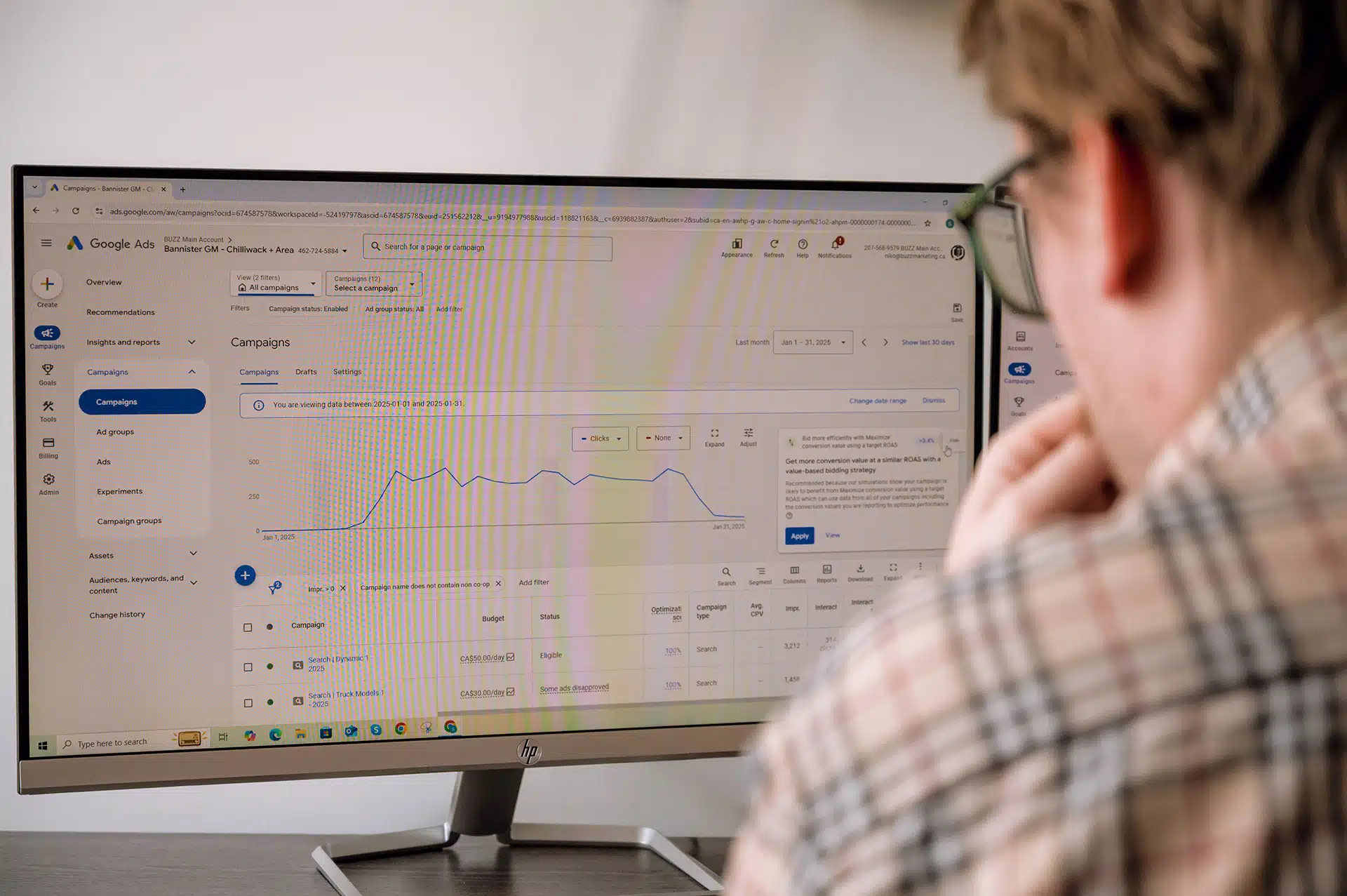 A person is looking at a computer screen displaying Google Ads campaign data, including graphs and campaign metrics.