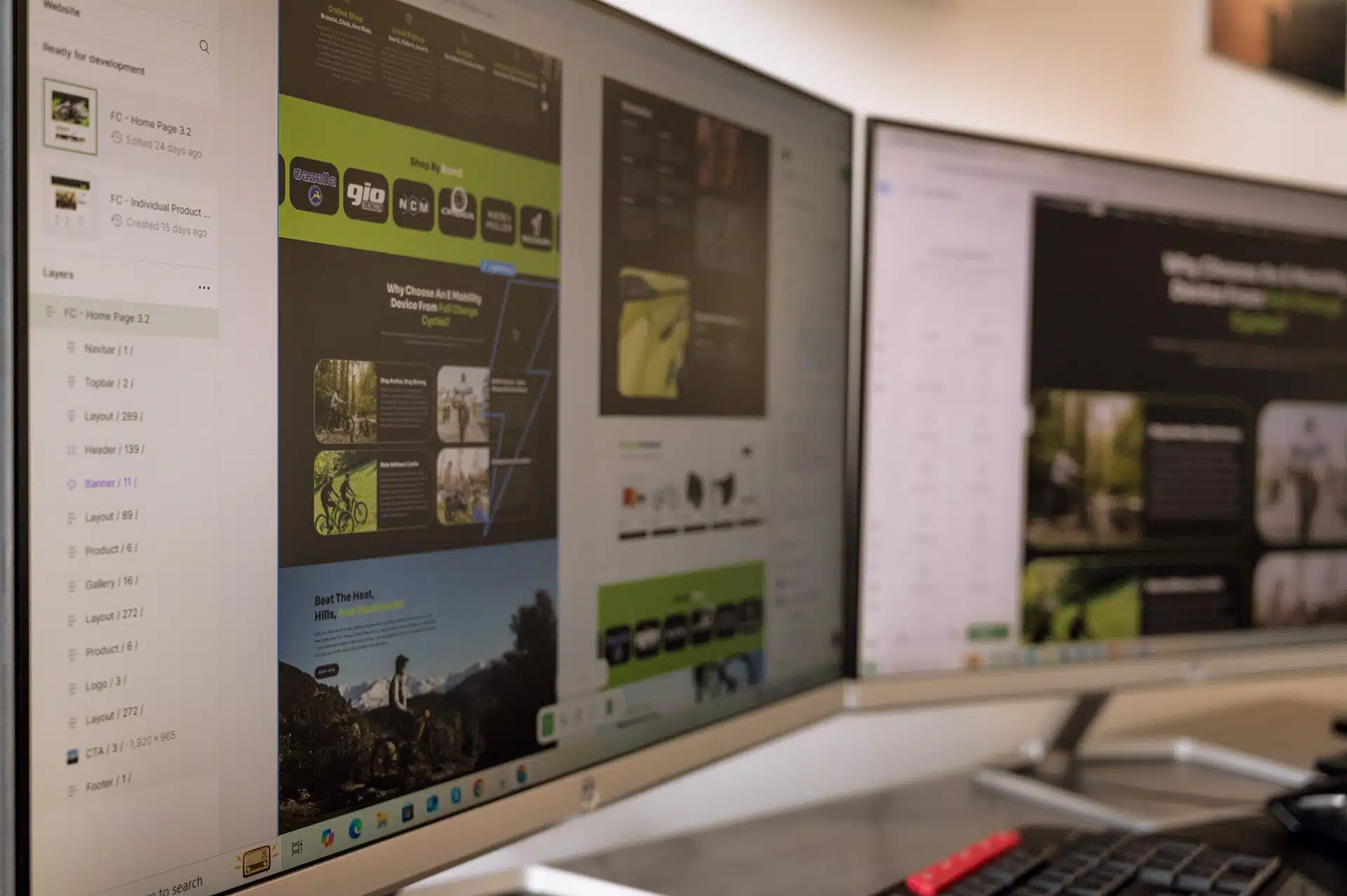 A close-up of computer screens displaying website design and development work, showcasing layouts and elements for a homepage related to cycling products.